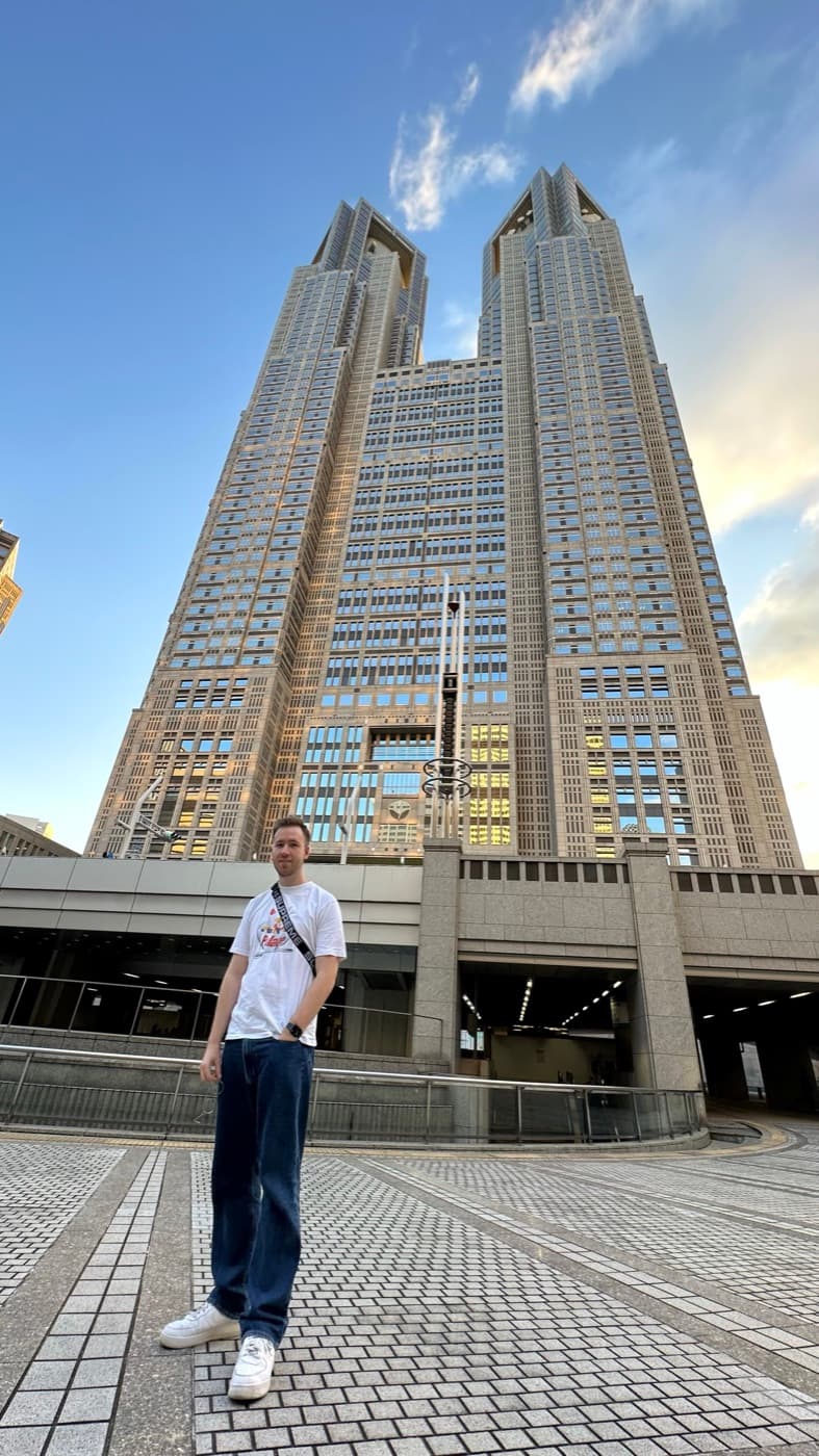 Die beiden Türme des Tokyo Metropolitan Government Building von unten, davor eine Person auf dem gepflasterten Vorplatz