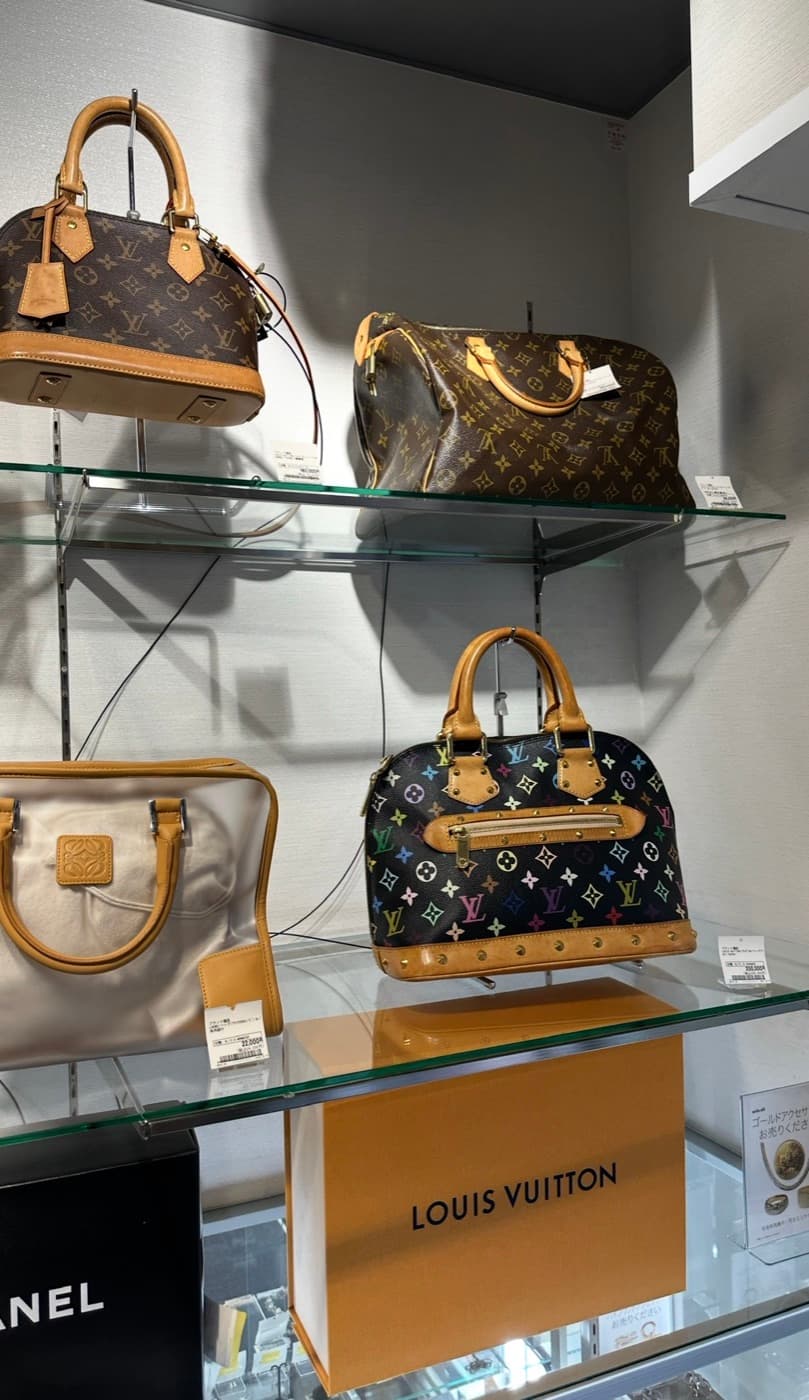 Second-Hand-Vitrine mit Louis-Vuitton-Taschen und Preisschildern in einem japanischen Resale-Shop
